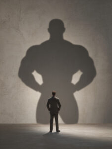 Homme en costume faisant face à une grande ombre symbolisant confiance en soi et potentiel professionnel.